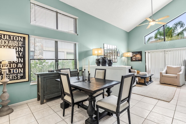 tiled dining room with ceiling fan and high vaulted ceiling