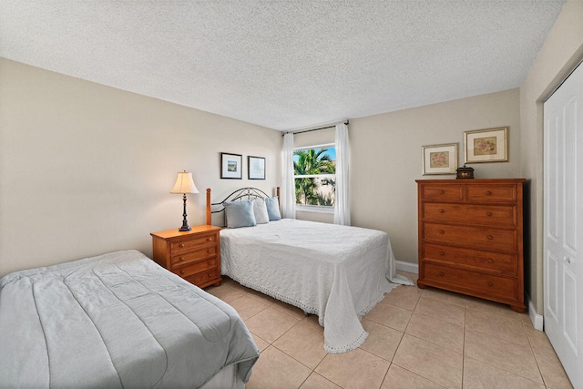 bedroom with a textured ceiling, a closet, and light tile patterned floors