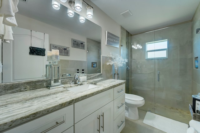 bathroom featuring tile walls, vanity, a shower with door, toilet, and tile patterned floors