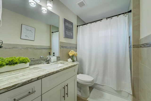 full bathroom featuring vanity, tile walls, shower / bath combo with shower curtain, and toilet