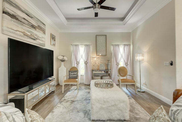 living room with ceiling fan, light wood-type flooring, and a tray ceiling