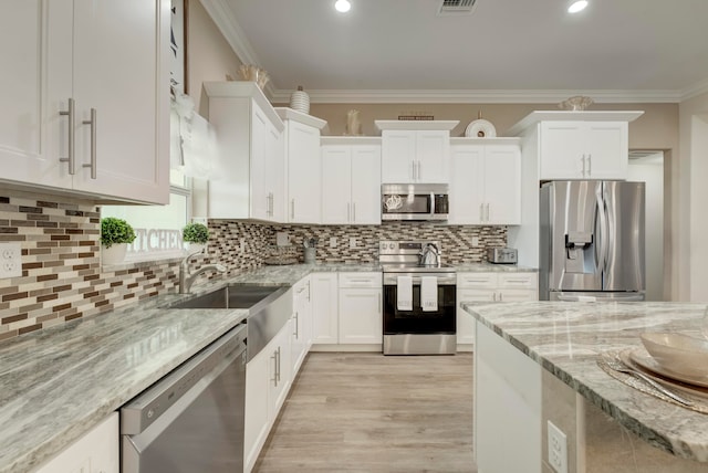 kitchen featuring tasteful backsplash, white cabinetry, stainless steel appliances, ornamental molding, and light stone countertops