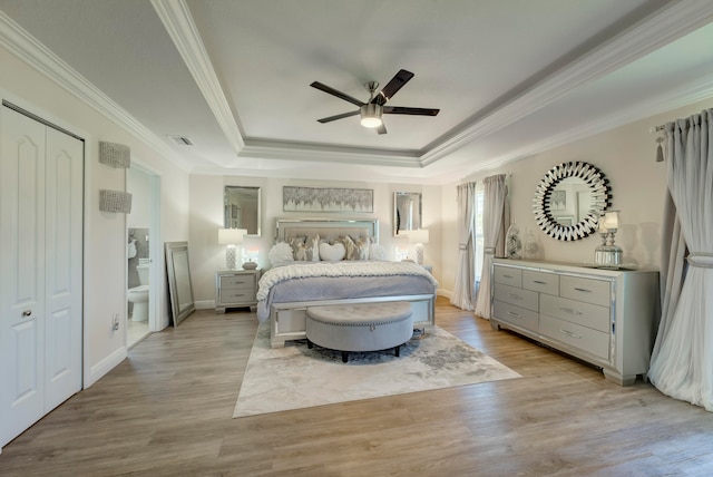 bedroom featuring light wood-type flooring, ceiling fan, a raised ceiling, and crown molding