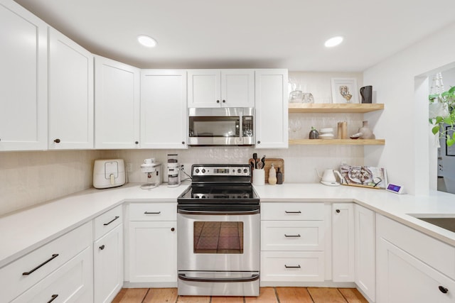 kitchen featuring tasteful backsplash, white cabinets, and appliances with stainless steel finishes