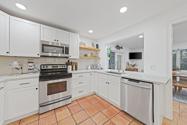 kitchen with stainless steel appliances, white cabinetry, tasteful backsplash, and sink