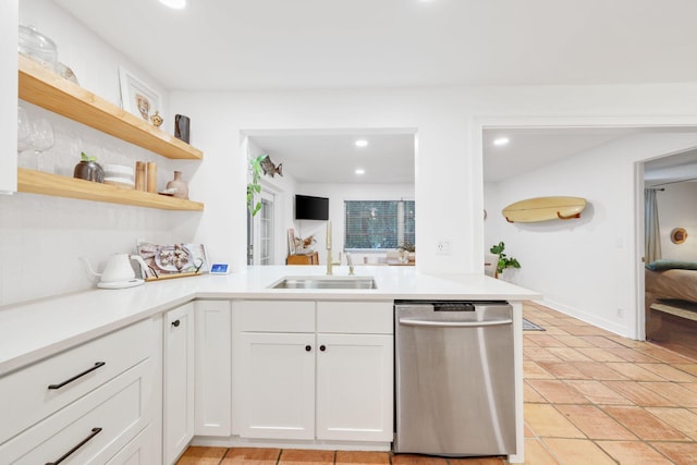 kitchen with kitchen peninsula, white cabinets, sink, light tile patterned floors, and dishwasher