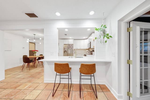 kitchen with a kitchen breakfast bar, sink, kitchen peninsula, white cabinetry, and stainless steel appliances