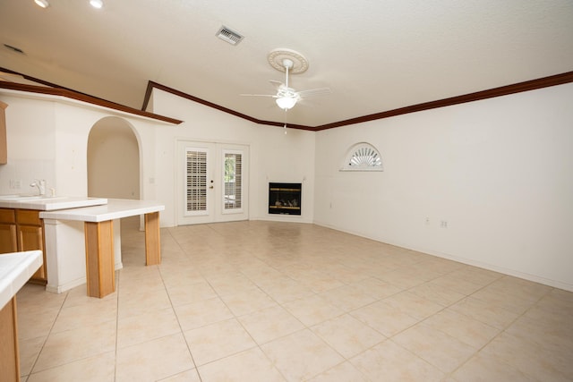 unfurnished living room with ceiling fan, lofted ceiling, and crown molding