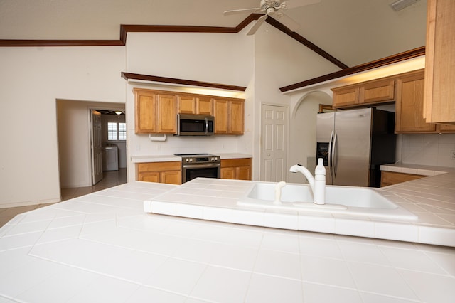 kitchen featuring appliances with stainless steel finishes, backsplash, washer / clothes dryer, and tile counters