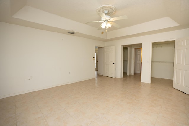 unfurnished bedroom with ceiling fan and a raised ceiling