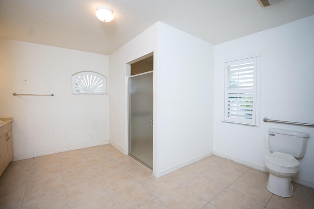 bathroom featuring tile patterned flooring, vanity, toilet, and walk in shower