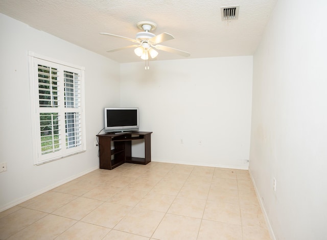 empty room featuring a textured ceiling, ceiling fan, and light tile patterned flooring