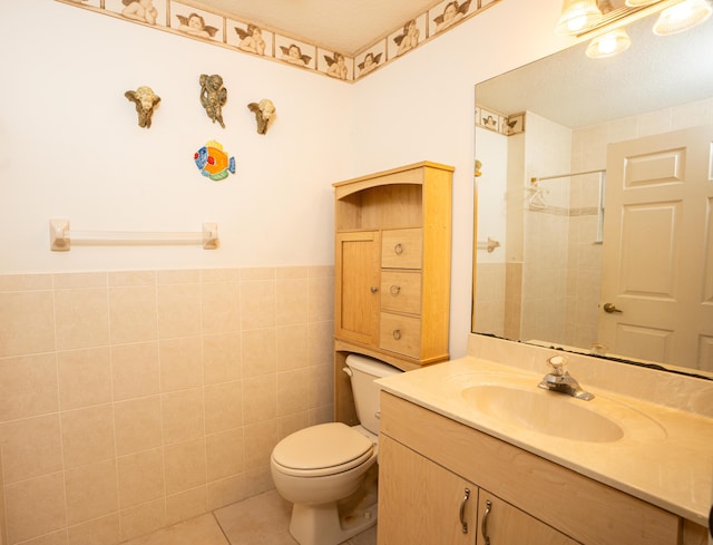 bathroom with tile patterned floors, a tile shower, vanity, tile walls, and toilet