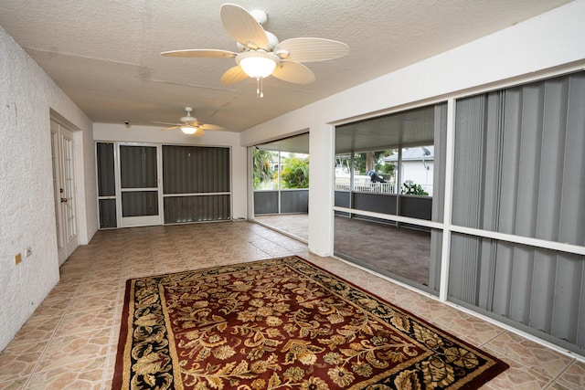 unfurnished sunroom featuring ceiling fan