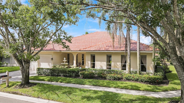 mediterranean / spanish-style home featuring a garage and a front yard