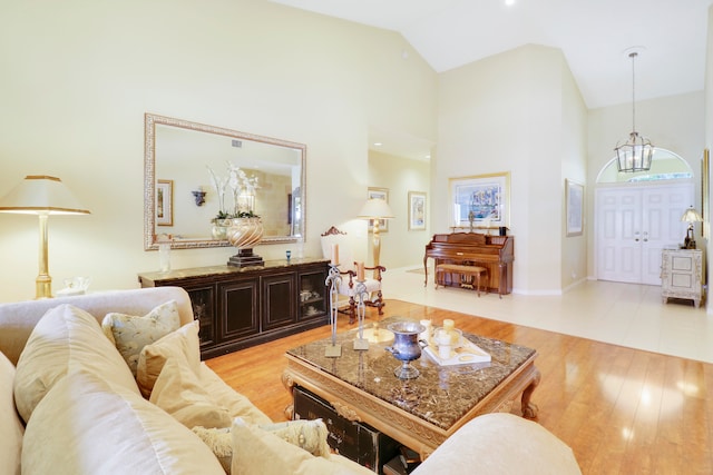 living room featuring a notable chandelier, light hardwood / wood-style flooring, and high vaulted ceiling