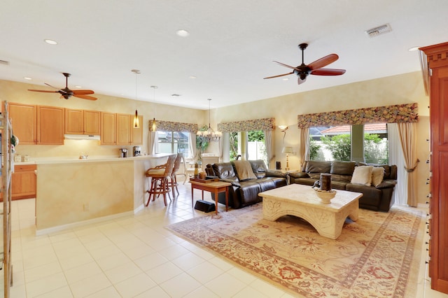 tiled living room with ceiling fan with notable chandelier