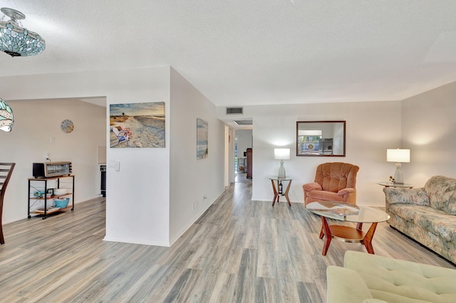 living room featuring a textured ceiling and light wood-type flooring