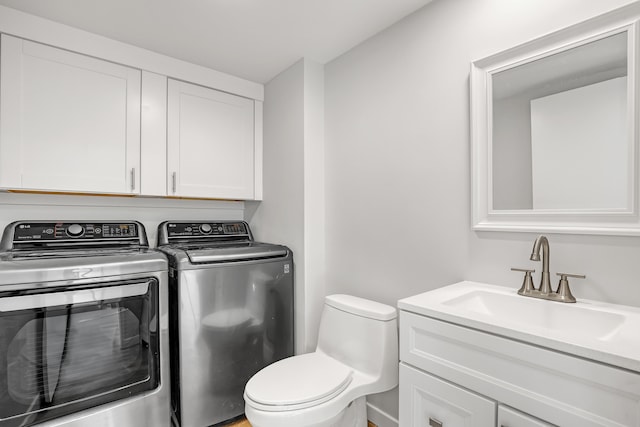 bathroom featuring washing machine and clothes dryer, vanity, and toilet