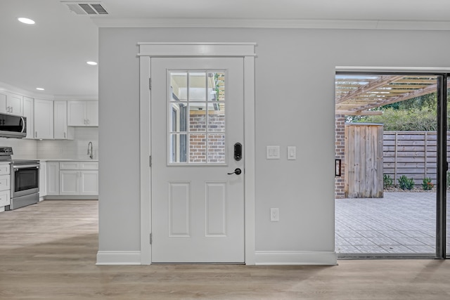 doorway featuring ornamental molding, sink, and light hardwood / wood-style flooring