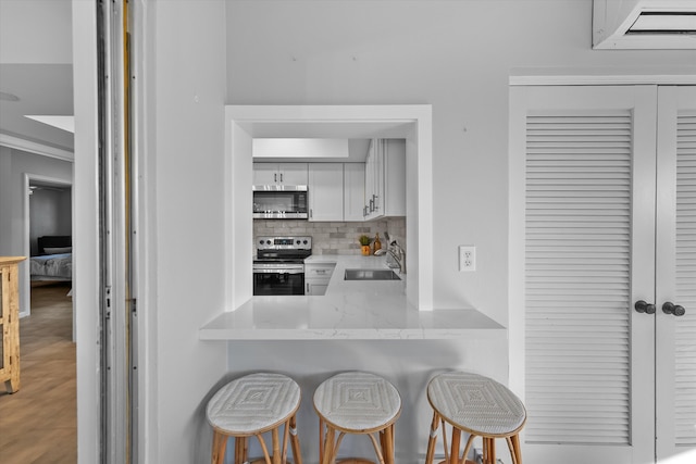 kitchen featuring sink, appliances with stainless steel finishes, backsplash, a kitchen breakfast bar, and white cabinets