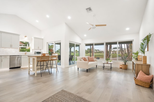 living room featuring light hardwood / wood-style flooring, high vaulted ceiling, and a healthy amount of sunlight