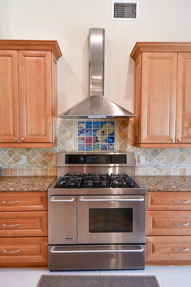 kitchen with tasteful backsplash, stainless steel range with gas stovetop, wall chimney range hood, and stone counters