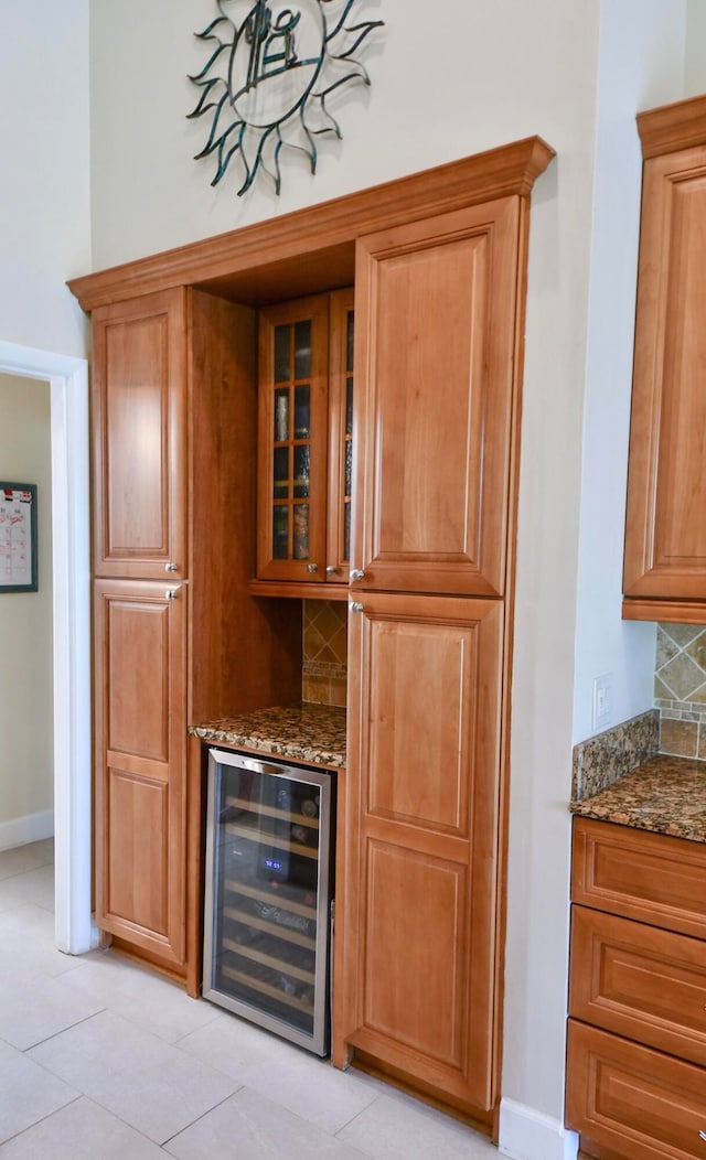 bar featuring dark stone countertops, wine cooler, light tile patterned floors, and tasteful backsplash