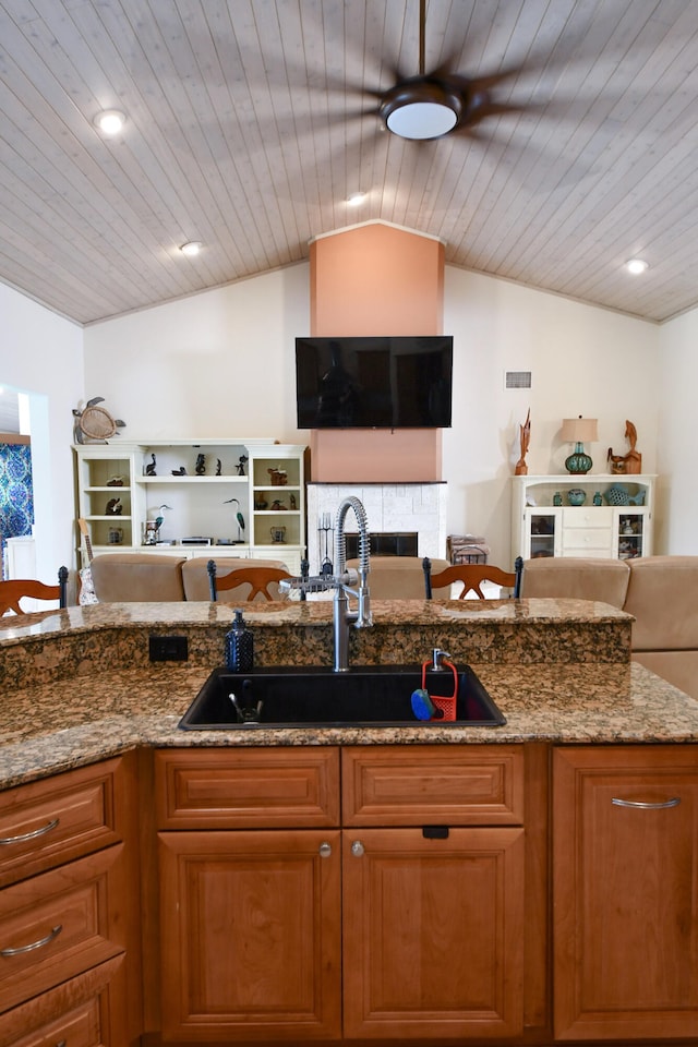 kitchen featuring lofted ceiling, wood ceiling, sink, and dark stone counters