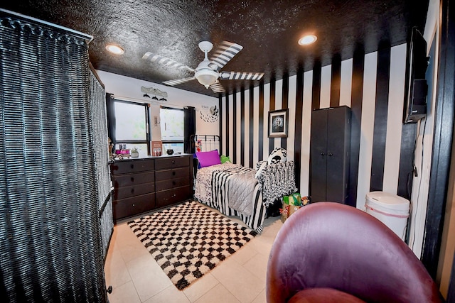 bedroom with ceiling fan, light tile patterned floors, and a textured ceiling