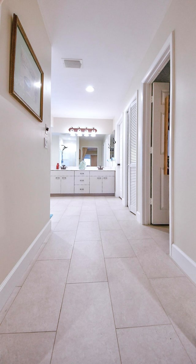 hall featuring light tile patterned flooring and sink