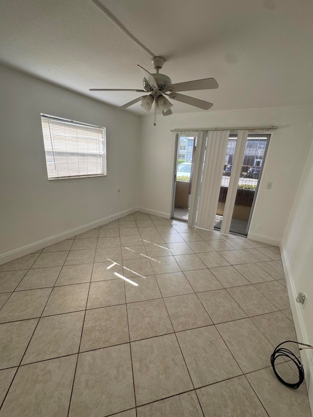 tiled spare room featuring ceiling fan and plenty of natural light