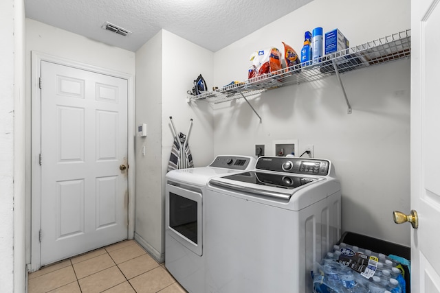 washroom with washer and clothes dryer, light tile patterned floors, and a textured ceiling