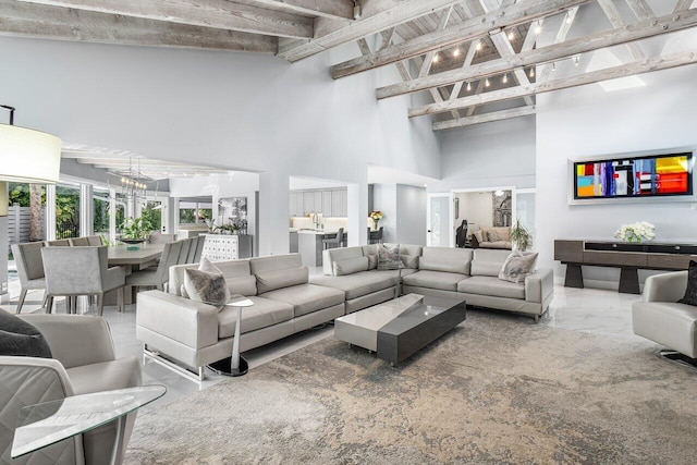 living room featuring beamed ceiling, a towering ceiling, and a notable chandelier