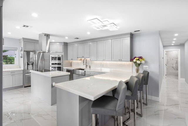 kitchen featuring a center island, tasteful backsplash, a breakfast bar area, kitchen peninsula, and exhaust hood