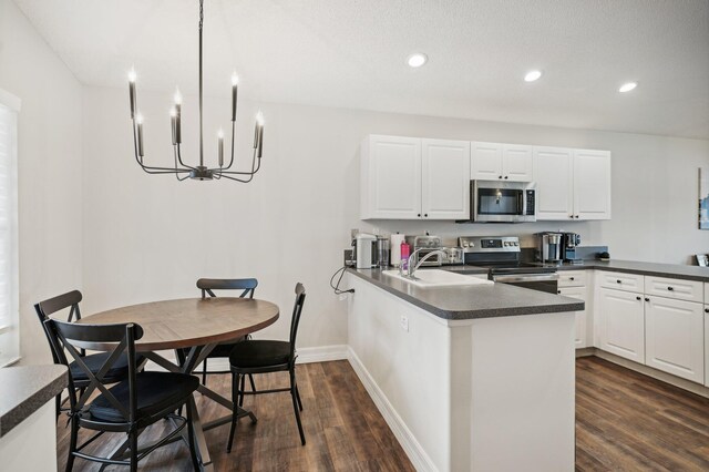 kitchen featuring kitchen peninsula, stainless steel appliances, dark wood-type flooring, sink, and white cabinetry