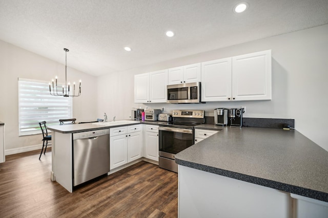 kitchen featuring kitchen peninsula, stainless steel appliances, dark wood-type flooring, white cabinets, and hanging light fixtures