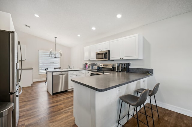 kitchen featuring kitchen peninsula, stainless steel appliances, white cabinets, dark hardwood / wood-style floors, and hanging light fixtures