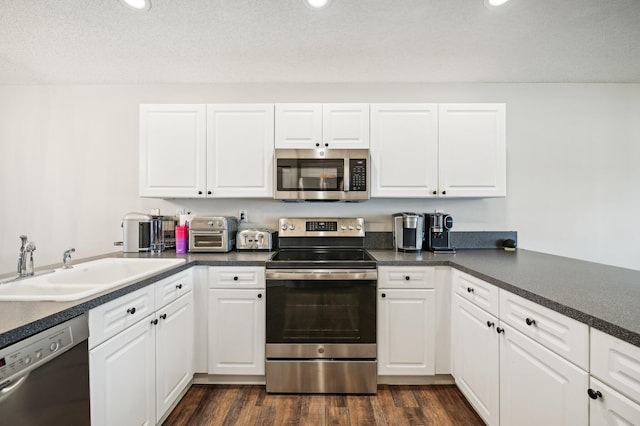 kitchen with white cabinets, sink, stainless steel appliances, and dark wood-type flooring