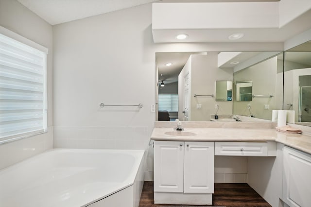 bathroom featuring a tub to relax in, hardwood / wood-style floors, vanity, and vaulted ceiling