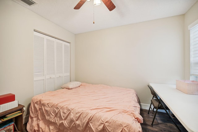 bedroom with ceiling fan, a closet, dark wood-type flooring, and a textured ceiling