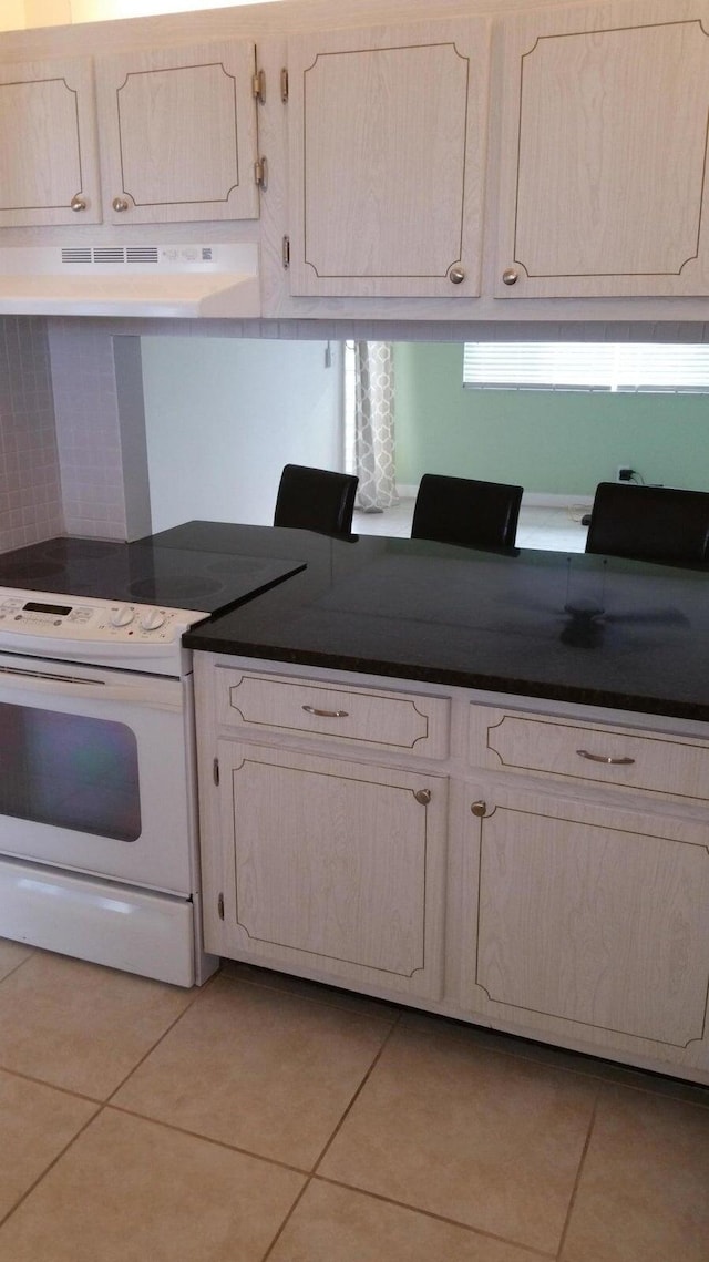 kitchen featuring white electric stove, light tile patterned flooring, and ventilation hood