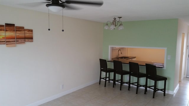 tiled dining space featuring indoor wet bar and ceiling fan with notable chandelier