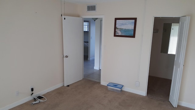 unfurnished bedroom with a closet and light colored carpet