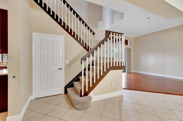 stairs with ornamental molding and tile patterned floors