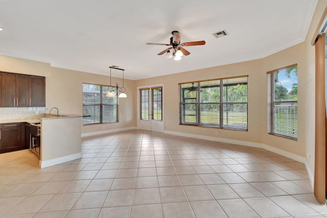 interior space featuring ornamental molding, a healthy amount of sunlight, and ceiling fan with notable chandelier