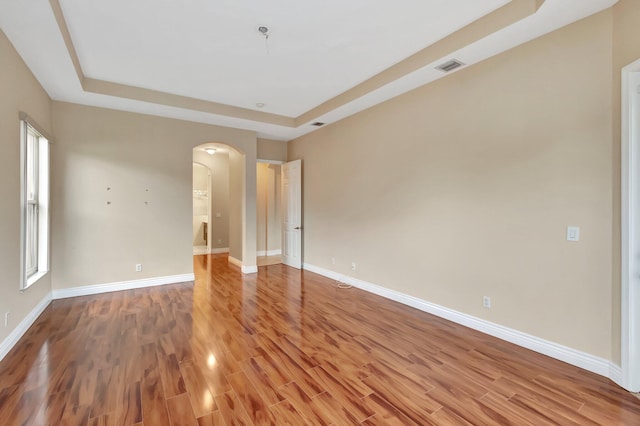 empty room featuring hardwood / wood-style flooring and a raised ceiling