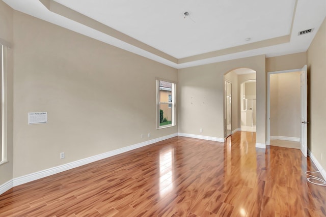 unfurnished room with a raised ceiling and light wood-type flooring