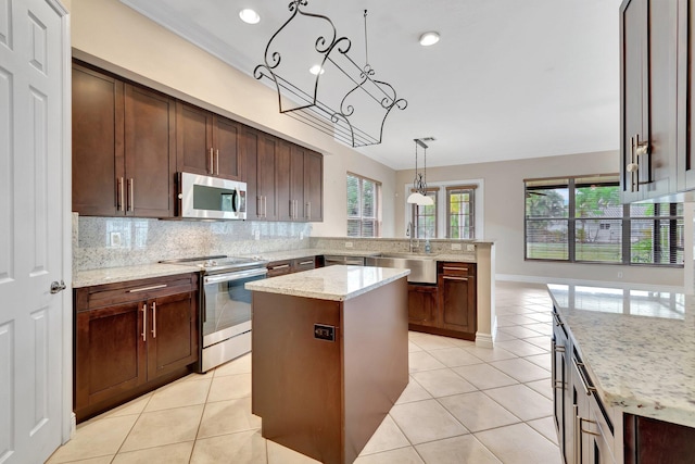 kitchen featuring sink, stainless steel appliances, a center island, light stone countertops, and decorative light fixtures