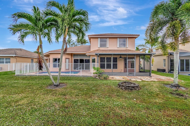 back of house featuring a lawn, a sunroom, a patio, and an outdoor fire pit